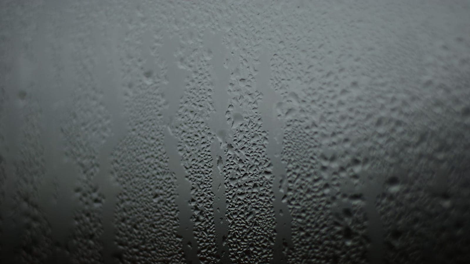 Cristal de una ventana cubierto de condensación, con regueros de agua bajando en vertical