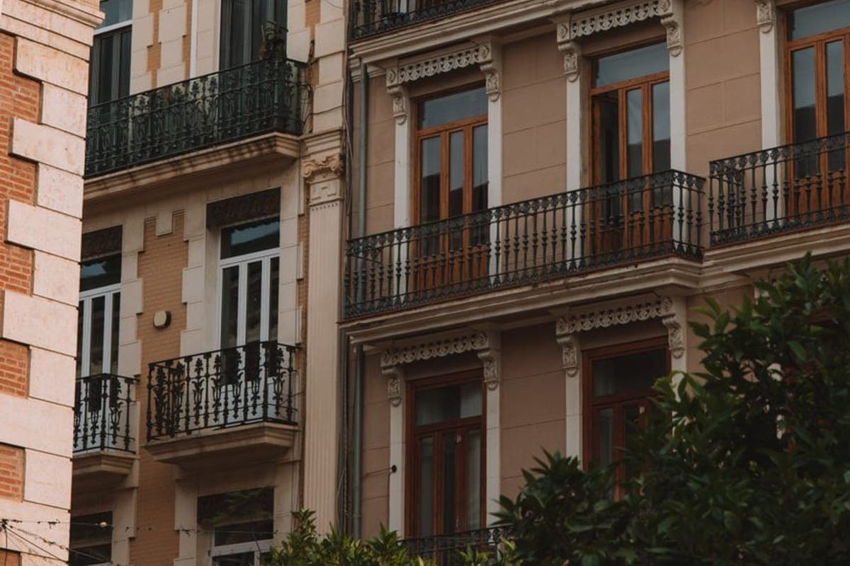 Fachada de un edificio antiguo de ciudad con balcones de forja, molduras de escayola y ventanas de madera