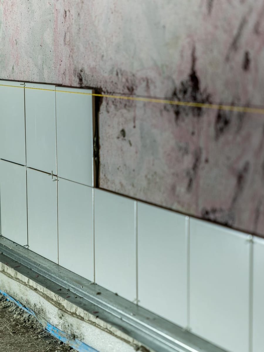 Pared alicatada solo hasta media altura, con crucetas entre las piezas y un hilo tendido como referencia