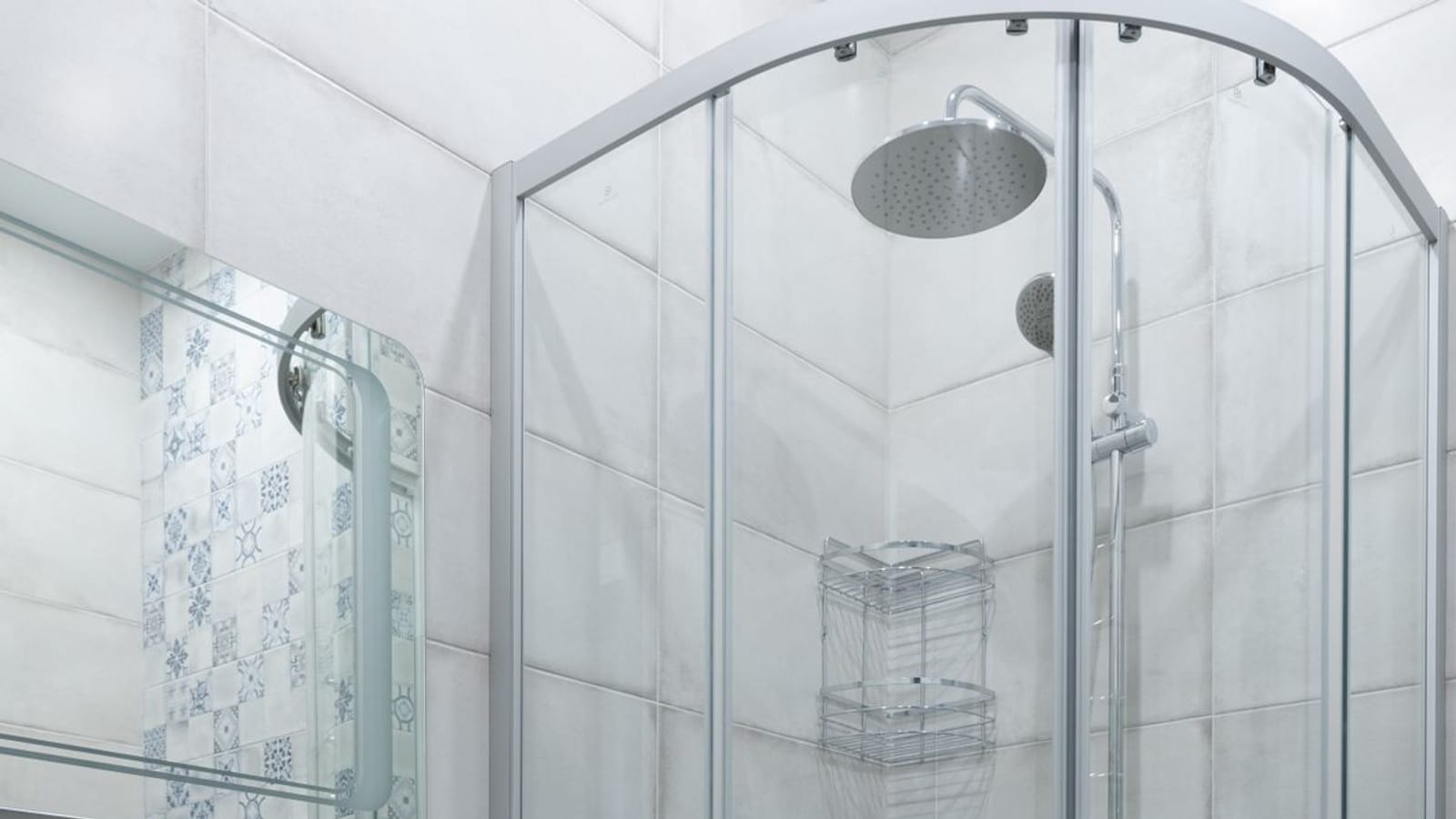 Baño claro con lavabo sobre mueble blanco y una mampara de ducha curva de ángulo con alcachofa de lluvia y grifo termostático